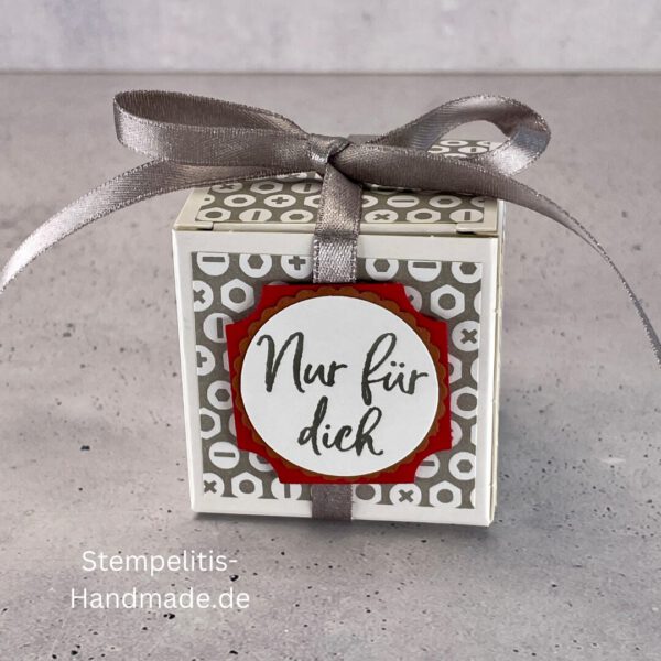 handdekorierte Geschenkschachtel mit Aufschrift „Nur für dich“, Geschenkschachtel mit grauem Muster und rotem Etikett, kleine Geschenkbox mit Satinband, Vorderansicht der Schachtel „Nur für dich“, offene Geschenkbox mit Inhalt, Detailaufnahme Schriftzug „Nur für dich“, stilvolle Geschenkverpackung mit Band